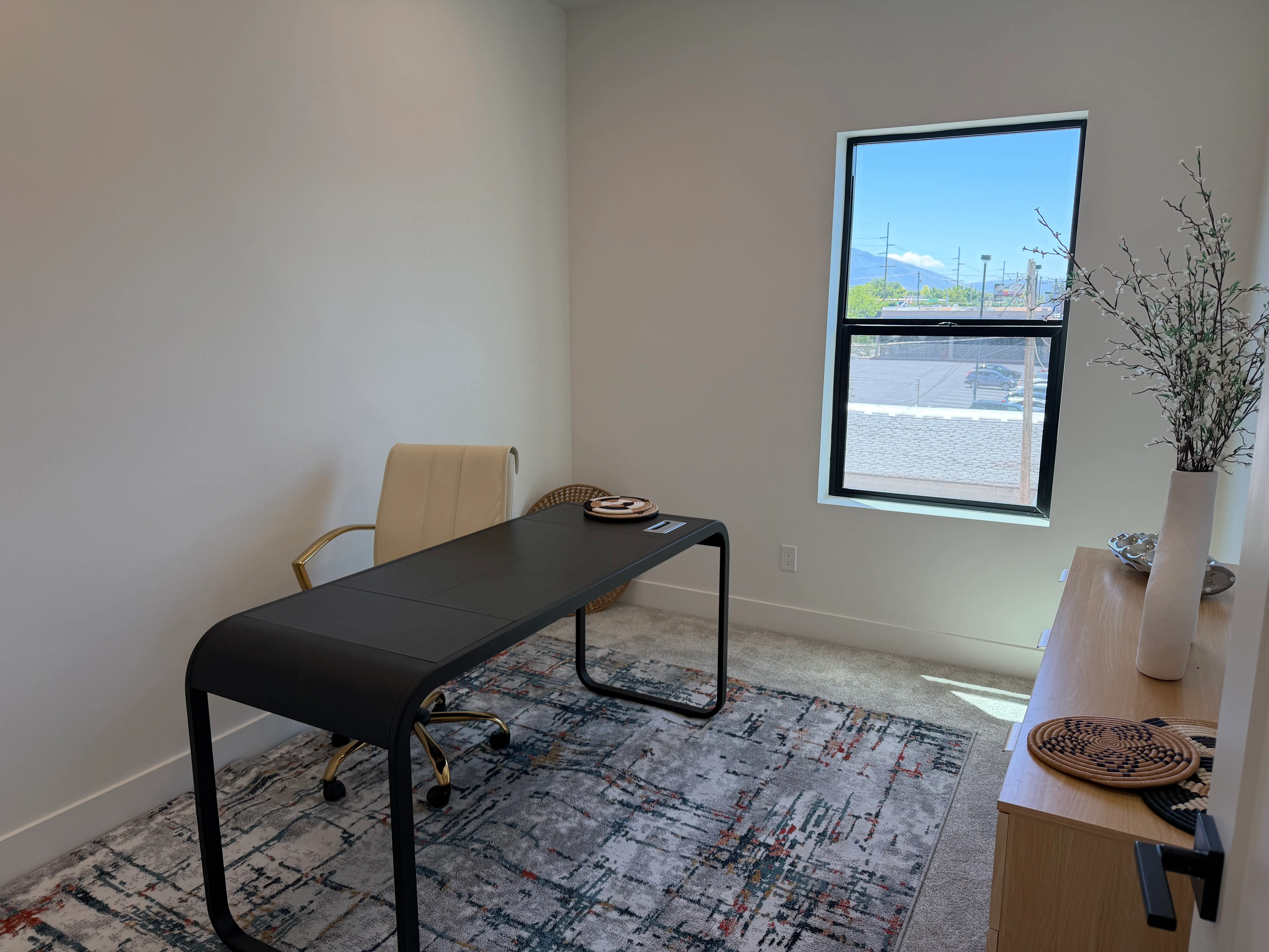 Flexible room staged as a home office with a desk and chair beside a window framing the mountains